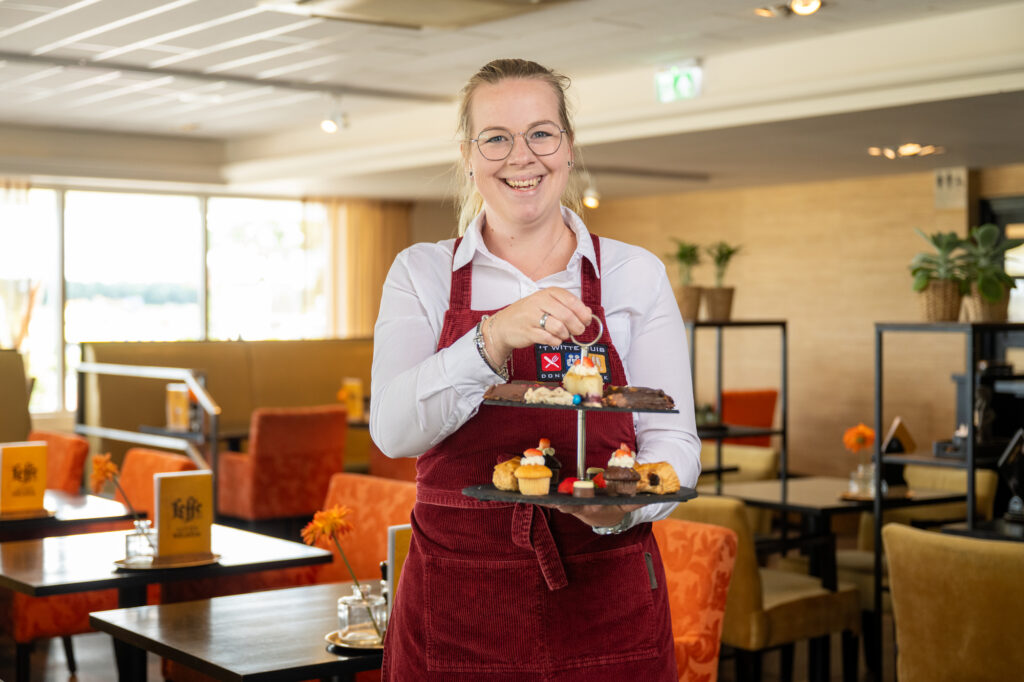 Medewerker serveert een etagère met lekkernijen in een restaurant