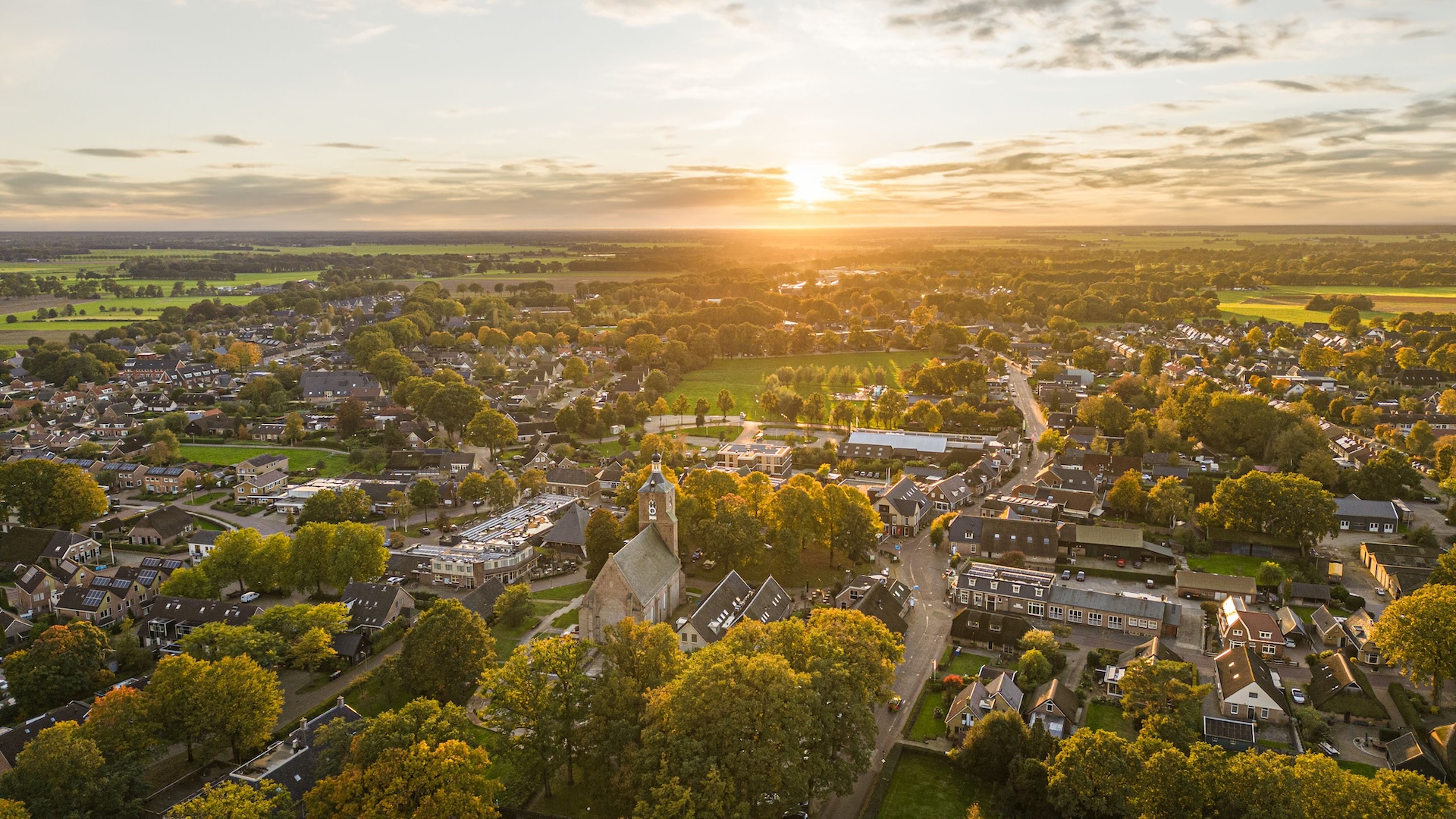 Luchtfoto van een dorp tussen het groen bij zonsondergang