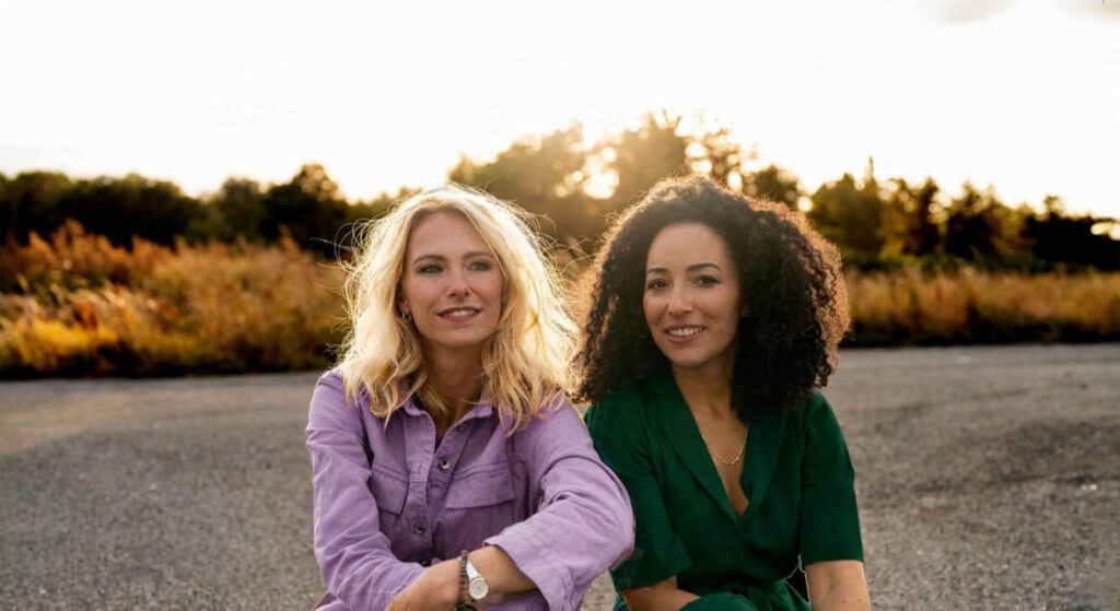 Twee vrouwen zitten naast elkaar op een weg bij zonsondergang